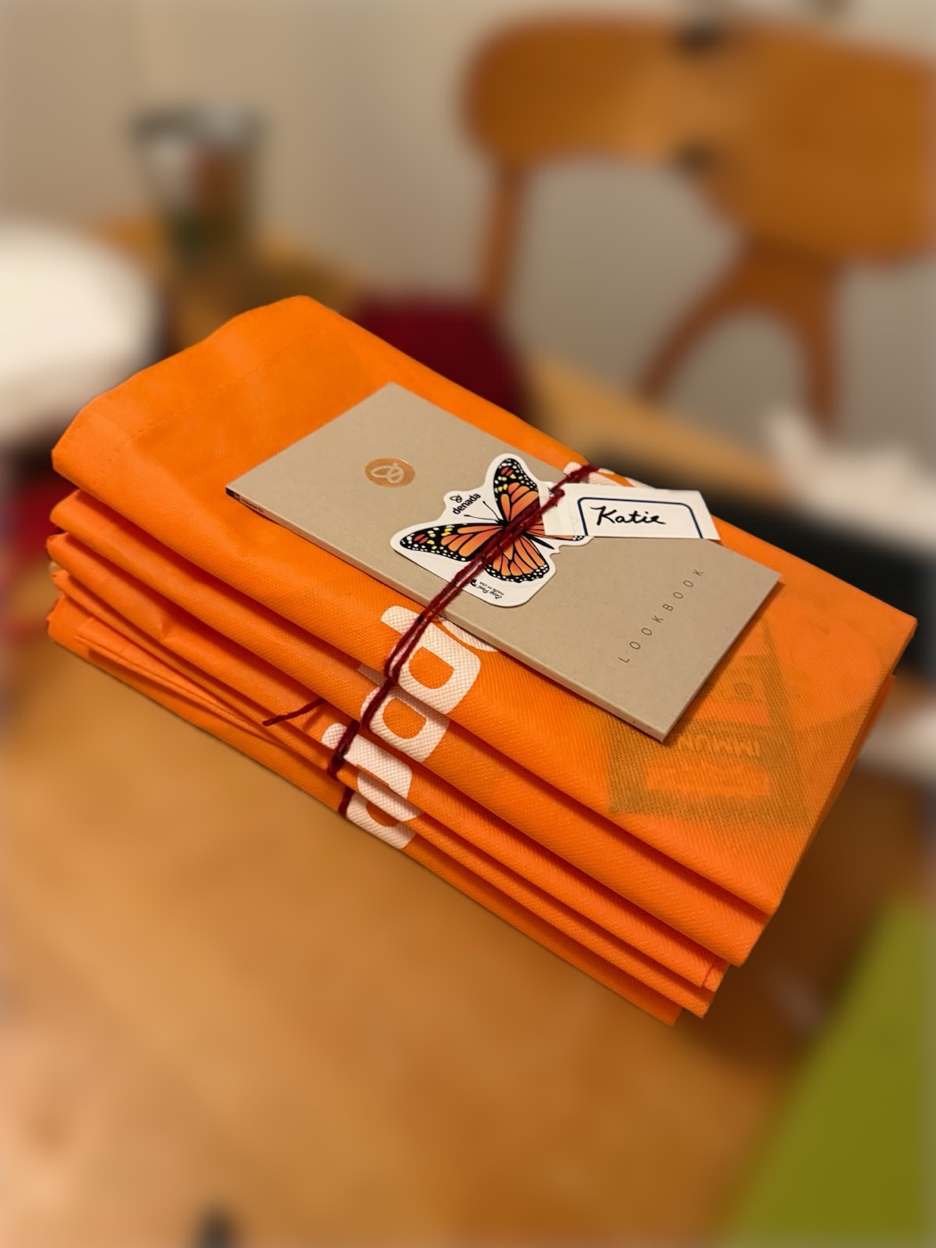 Orange Denada wellness bags with the printed Email Design Lookbook and a monarch butterfly sticker